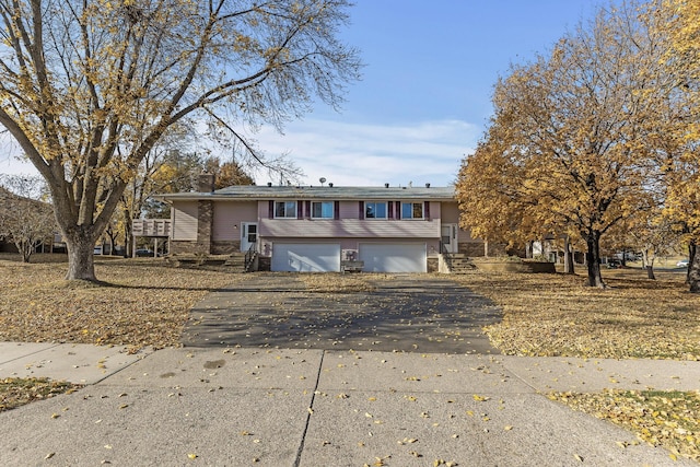 view of front of home featuring a garage, stone siding, and aphalt driveway