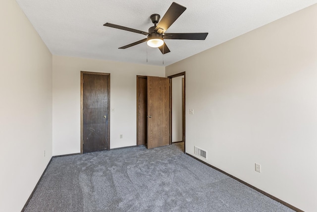 unfurnished bedroom featuring ceiling fan, a textured ceiling, and dark colored carpet