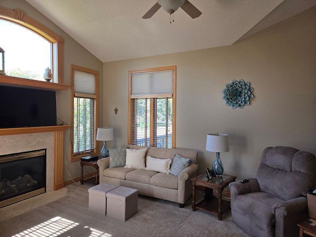 carpeted living room with a wealth of natural light, lofted ceiling, ceiling fan, and a fireplace