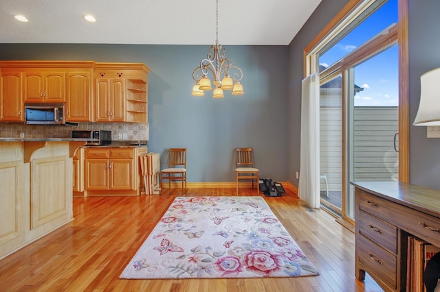 kitchen with tasteful backsplash, pendant lighting, an inviting chandelier, and light hardwood / wood-style floors