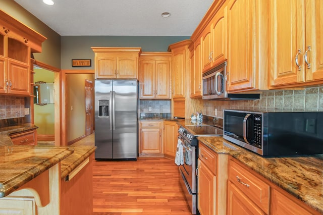 kitchen featuring light wood-type flooring, appliances with stainless steel finishes, a textured ceiling, stone countertops, and decorative backsplash