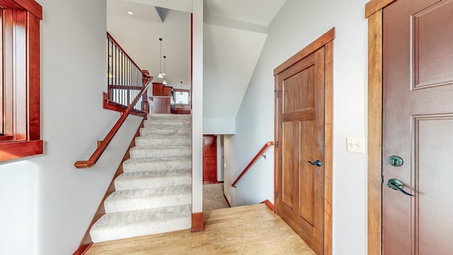 stairs featuring lofted ceiling and hardwood / wood-style floors