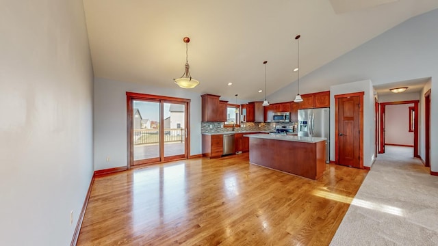 kitchen with appliances with stainless steel finishes, a kitchen island, light hardwood / wood-style floors, pendant lighting, and high vaulted ceiling