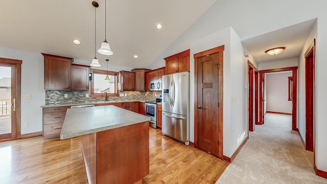 kitchen with a kitchen island, light hardwood / wood-style floors, stainless steel appliances, vaulted ceiling, and decorative light fixtures