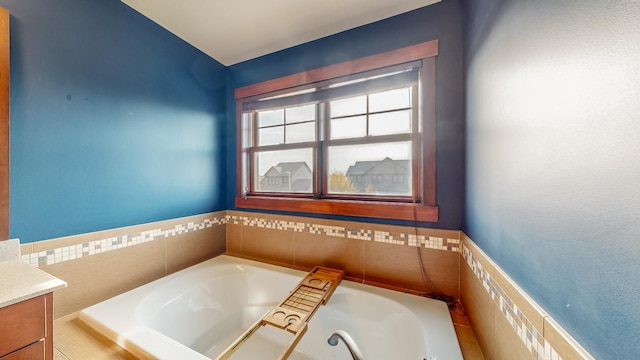 bathroom featuring vanity and tiled tub