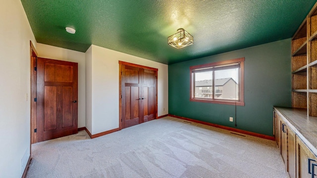 unfurnished bedroom featuring light carpet, a textured ceiling, and a closet