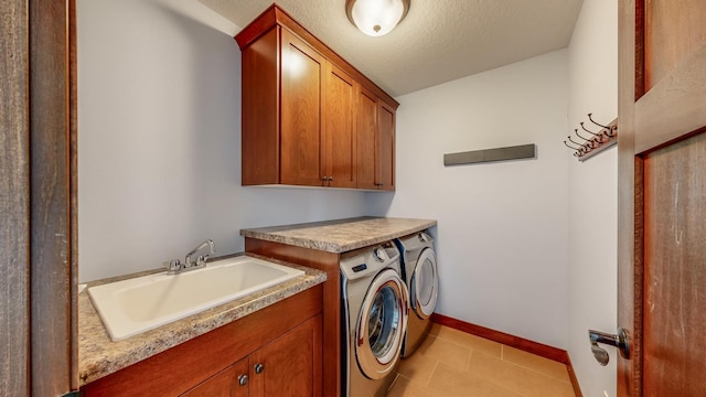 laundry area with cabinets, light tile patterned floors, washer and dryer, a textured ceiling, and sink