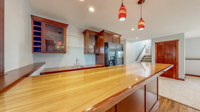 kitchen with sink, black refrigerator with ice dispenser, decorative light fixtures, and hardwood / wood-style floors