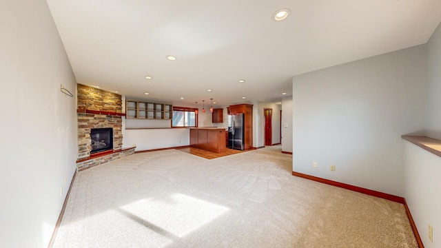 unfurnished living room with a stone fireplace and light colored carpet