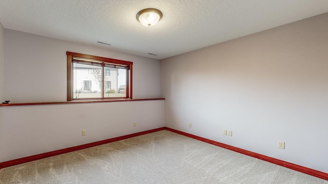 carpeted empty room featuring a textured ceiling