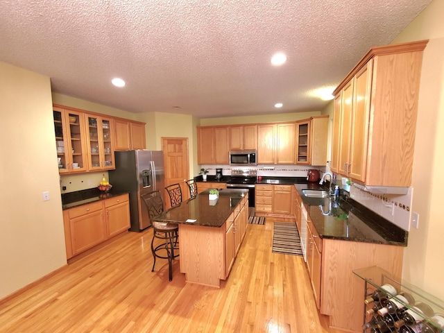 kitchen with a center island, stainless steel appliances, light wood-type flooring, a kitchen bar, and a sink