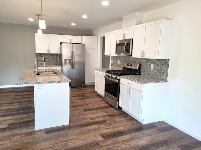 kitchen with sink, appliances with stainless steel finishes, pendant lighting, and white cabinets