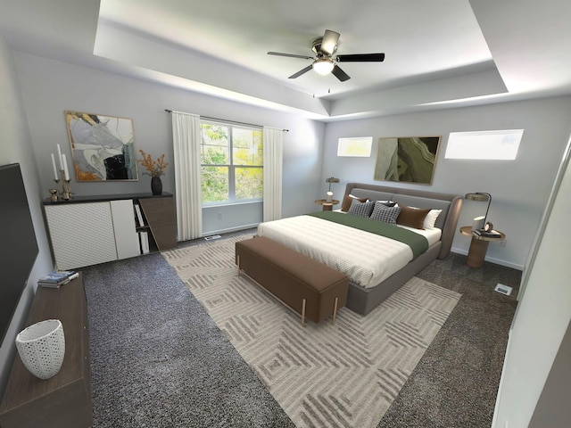 bedroom with dark colored carpet, a tray ceiling, and ceiling fan