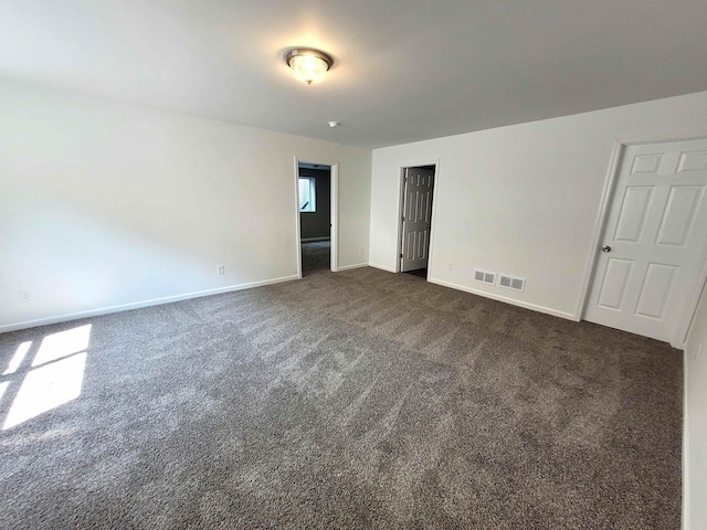 spare room with dark colored carpet