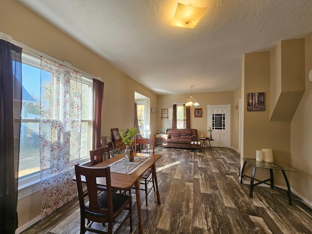 dining space featuring dark wood-type flooring, a healthy amount of sunlight, and a textured ceiling