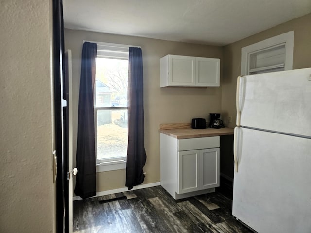 kitchen with white cabinetry, wooden counters, dark wood-type flooring, and white fridge