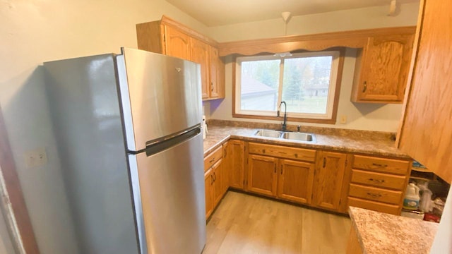 kitchen with light wood-type flooring, sink, and stainless steel fridge