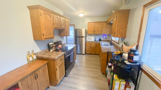 kitchen with light hardwood / wood-style floors, stainless steel fridge, black / electric stove, and sink