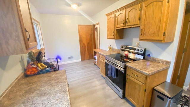 kitchen with stainless steel electric range oven and light hardwood / wood-style flooring