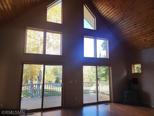 unfurnished living room with dark wood-type flooring, high vaulted ceiling, and a wood stove