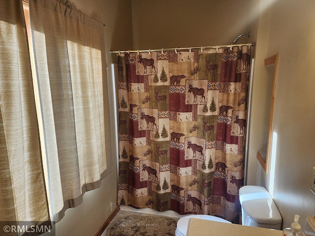 bathroom featuring a shower with shower curtain and toilet