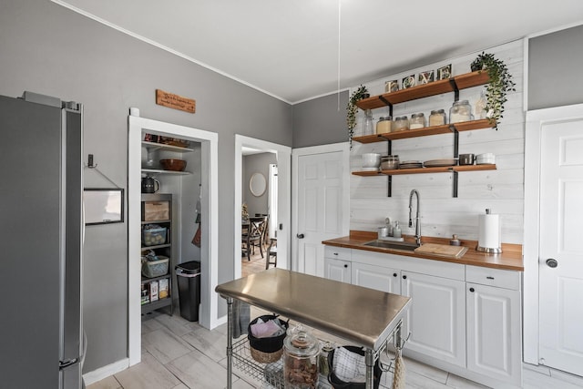 kitchen featuring white cabinets, wood counters, sink, and stainless steel fridge