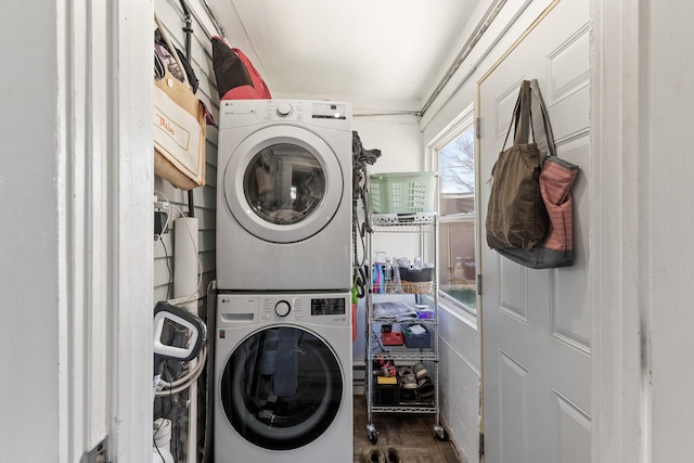 laundry room featuring parquet flooring and stacked washer and clothes dryer