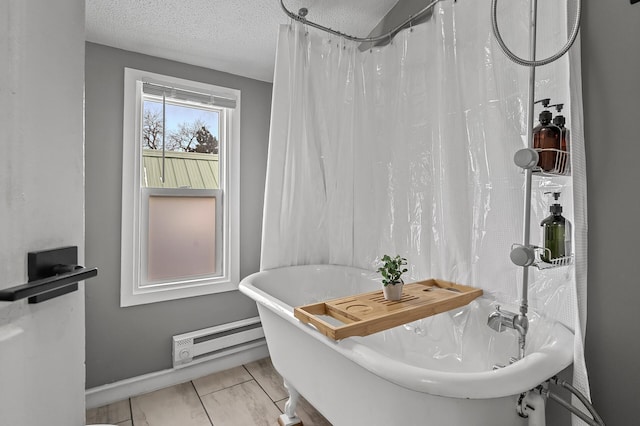 bathroom featuring a tub, a textured ceiling, and a baseboard heating unit