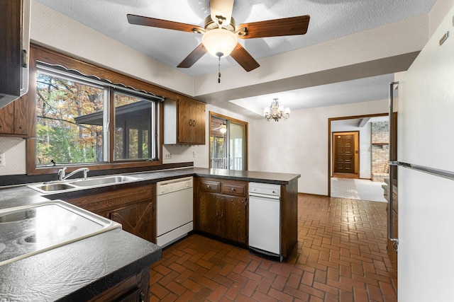 kitchen with kitchen peninsula, a textured ceiling, ceiling fan with notable chandelier, sink, and white appliances