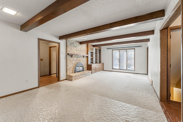 unfurnished living room featuring beam ceiling, a textured ceiling, a fireplace, and wood walls