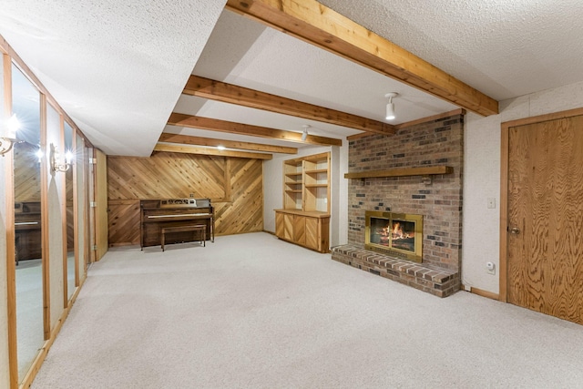 carpeted living room featuring wood walls, beam ceiling, a textured ceiling, and a brick fireplace