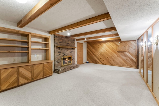 unfurnished living room featuring wood walls, a fireplace, a textured ceiling, light carpet, and beamed ceiling