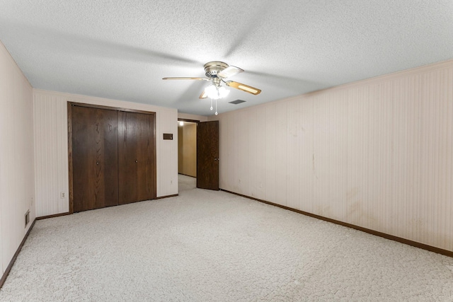 unfurnished bedroom with light carpet, a closet, a textured ceiling, and ceiling fan