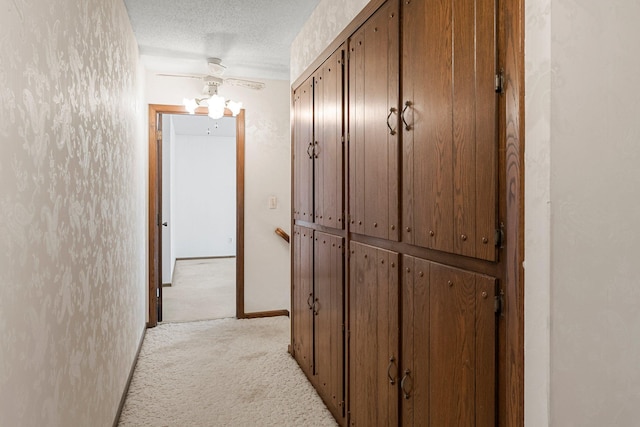 hall with a textured ceiling and light colored carpet