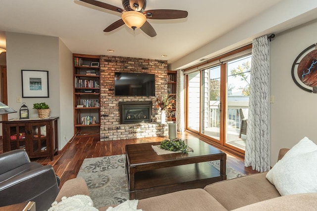 living room featuring ceiling fan, dark hardwood / wood-style flooring, and a brick fireplace