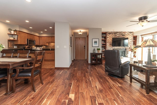 interior space featuring ceiling fan, a brick fireplace, and dark hardwood / wood-style flooring