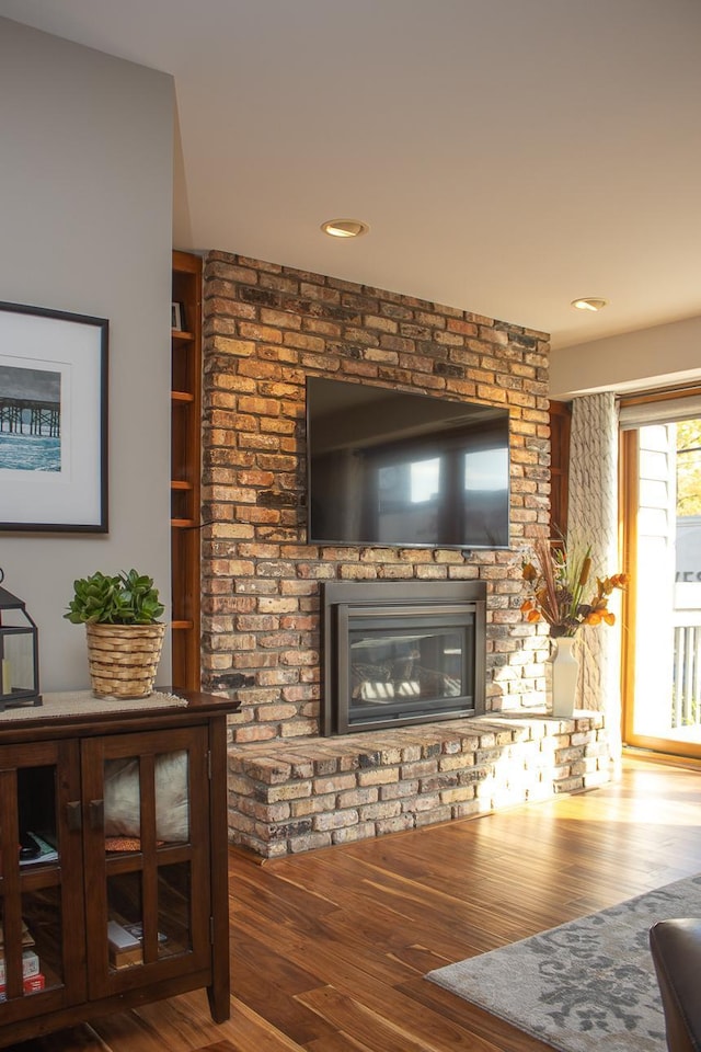 living room featuring a brick fireplace and wood finished floors