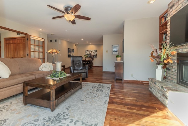 living room with recessed lighting, a ceiling fan, a brick fireplace, wood finished floors, and baseboards