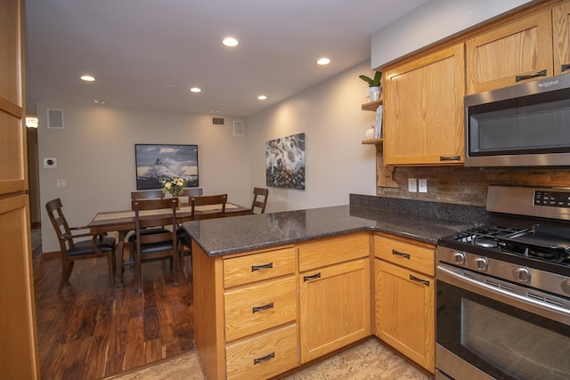 kitchen featuring stainless steel appliances, recessed lighting, visible vents, dark stone countertops, and a peninsula