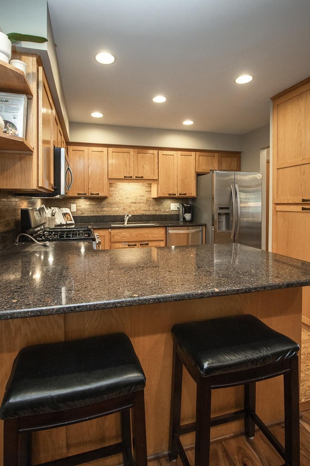 kitchen with stainless steel appliances, a peninsula, a kitchen bar, and decorative backsplash