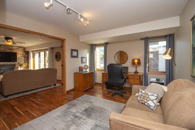 living room featuring a fireplace, wood finished floors, a ceiling fan, and rail lighting