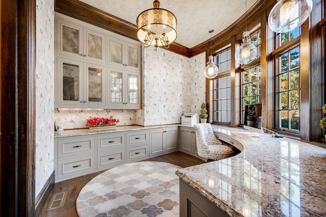 10675 Cavallo Rdg, Eden Prairie, MN 55347 - kitchen with wallpapered walls, light stone countertops, crown molding, glass insert cabinets, and a chandelier