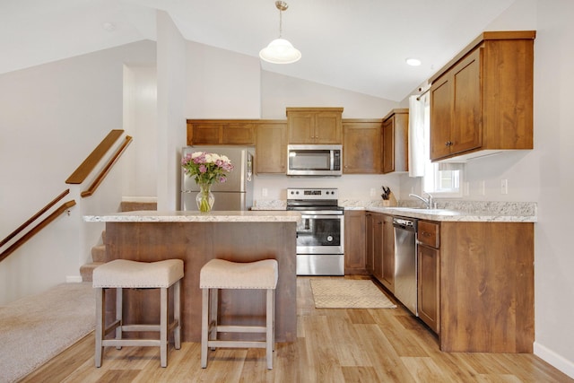 kitchen featuring stainless steel appliances, vaulted ceiling, and light wood-type flooring