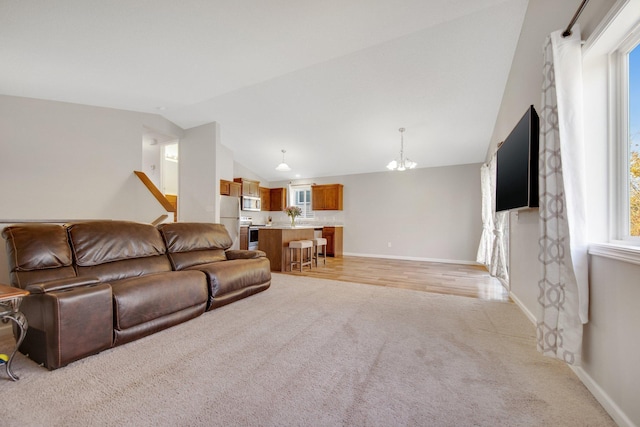 living room with light hardwood / wood-style flooring, a chandelier, and vaulted ceiling