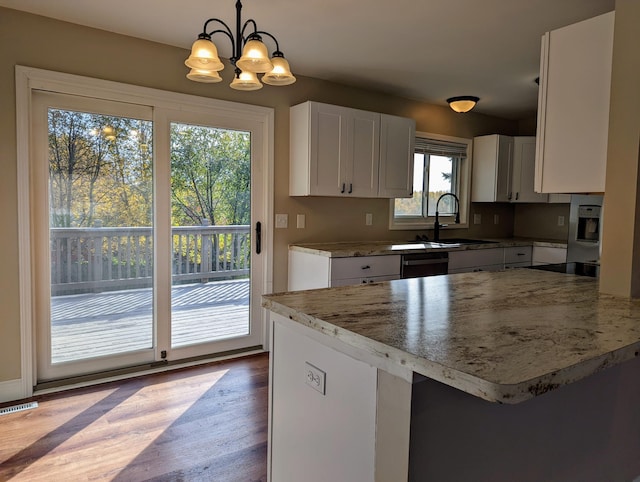 kitchen featuring hardwood / wood-style floors, sink, white cabinetry, and decorative light fixtures