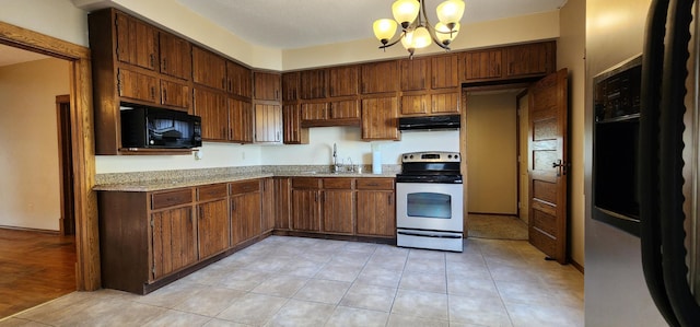 kitchen with sink, white range with electric cooktop, light wood-type flooring, an inviting chandelier, and light stone counters