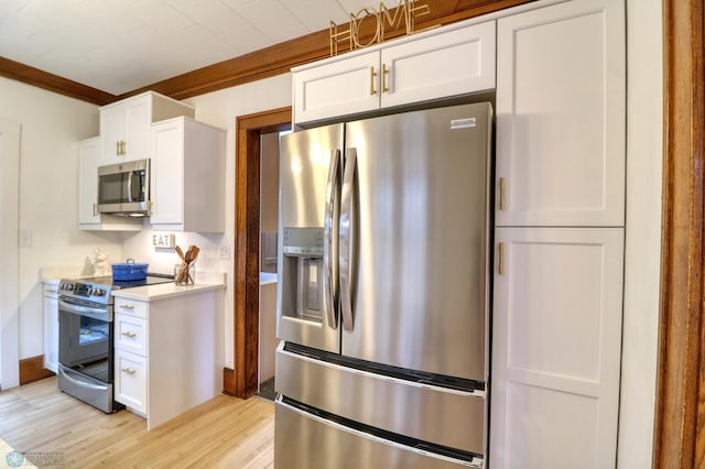 kitchen with ornamental molding, appliances with stainless steel finishes, white cabinets, and light hardwood / wood-style floors