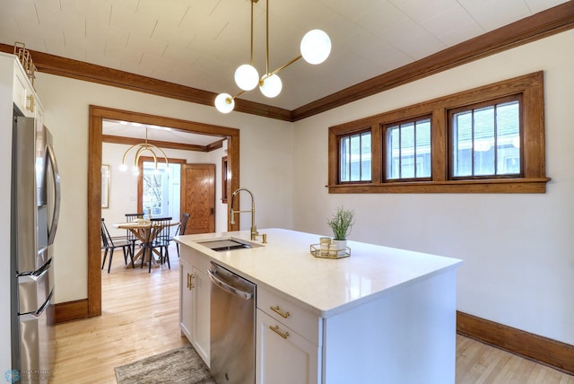 kitchen featuring appliances with stainless steel finishes, sink, white cabinetry, decorative light fixtures, and a kitchen island with sink