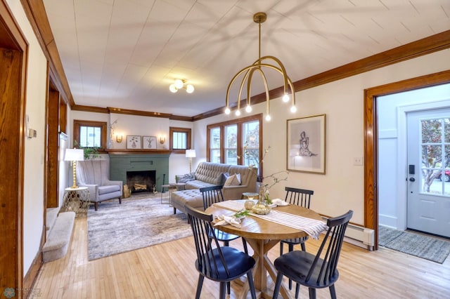 dining space featuring a wealth of natural light, ornamental molding, light hardwood / wood-style flooring, and a fireplace