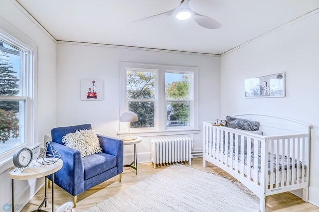 bedroom with crown molding, multiple windows, radiator heating unit, and ceiling fan